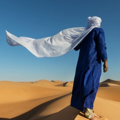 Un bereber del desierto contempla el horizonte en las dunas de Marruecos, una imagen que evoca la auténtica aventura y cultura de nuestro circuito de 8 días Marrakech y Fez con desierto.