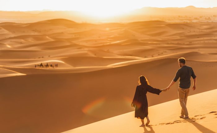 Contacta con Morocco Índigo Tours y Descubre Marrakech y el Desierto Pareja sobre las dunas del desierto y disfrutando del atardecer y las vistas del desierto