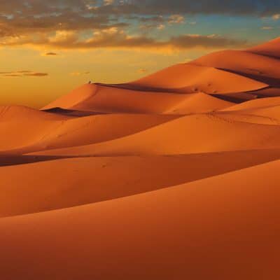 Espectacular atardecer sobre las majestuosas dunas de Merzouga, un paisaje inolvidable que te espera en nuestra aventura de 8 días por el desierto.